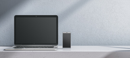 Close up of empty laptop and cellphone on gray desk. Concrete wall background. Device presentation and online education concept. Mock up, 3D Rendering. - obrazy, fototapety, plakaty