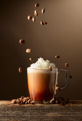 Coffee and chocolate drink with whipped cream on a brown background.
