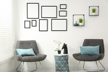 Stylish room interior with empty frames hanging on white wall
