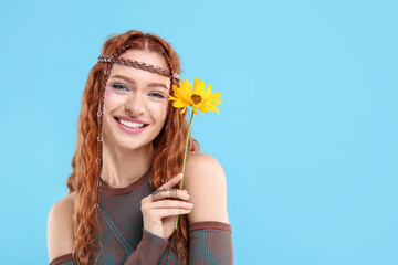 Beautiful young hippie woman with sunflower on light blue background, space for text