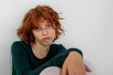 sad teenage girl with red hair squats