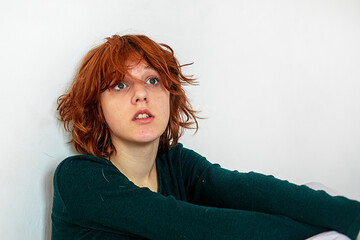sad teenage girl with red hair squats