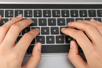 Hands on black laptop keyboard close up view