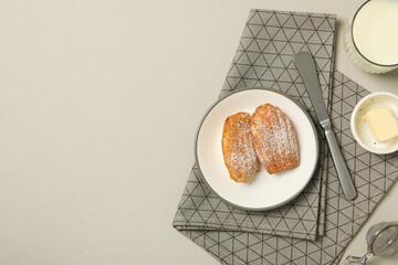 Madeleine cakes, flour, butter and towel on gray background, space for text