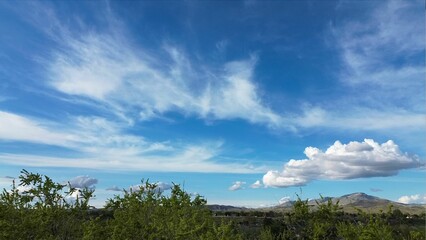 Peaceful landscape featuring a blue sky with white clouds above a distant mountain