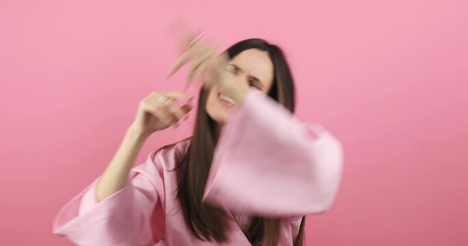 Emotions of people. Girl dancing and singing. Funny unusual brunette woman hair having fun, chill, grimaces, smiling, dancing in studio against pink background. Music, dance concept.