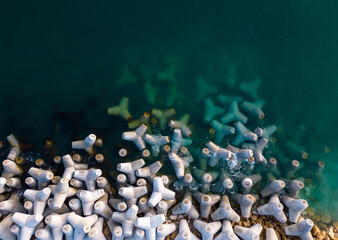 Aerial drone view of a breakwater. breakwater in the sea, a collection of concrete tetrapod breakers - obrazy, fototapety, plakaty