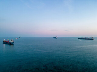 Several cargo ships in a sea bay are waiting in a queue to enter the port, an aerial view