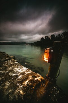 Black clouds over an Illuminated concrete pier at sunrise, Livingston, Izabal Department, Guatemala