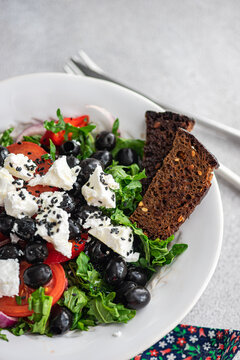 Overhead view of a bowl of greek salad with rye bread on a table