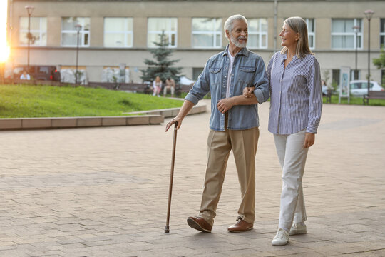 Senior man with walking cane and mature woman outdoors. Space for text - Powered by Adobe