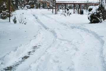 A plowed road in a snowy landscape. The aftermath of a blizzard. The trees and rocks are covered with white snow. A blizzard has left a thick layer of snow on the ground and the trees.