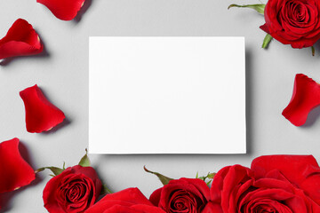 Blank card, beautiful red roses and petals on grey background, flat lay. Space for text