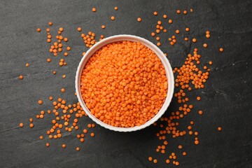 Raw red lentils in bowl on grey textured table, top view