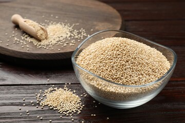 Dry quinoa seeds in bowl and scoop on wooden table