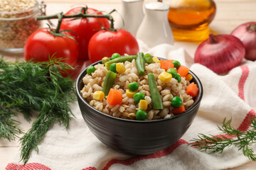 Delicious pearl barley with vegetables and other products on table, closeup