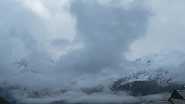 4K shot of storm clouds rolling over snow covered mountains in Keylong, India. Snow storm during winter in Indian Himalayas. Time-lapse footage of earth landscape with moving clouds.