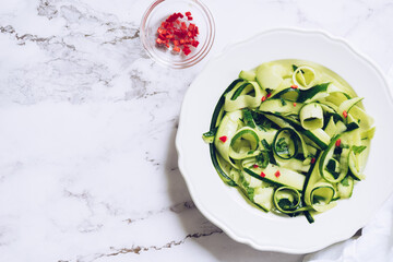 Healthy salad with fresh zucchini, mint and hot chilli pepper on a white plate