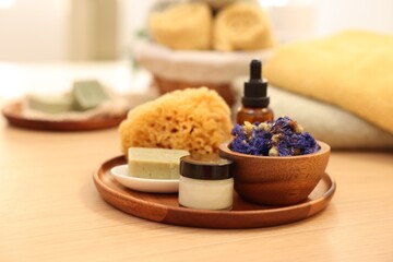Dry flowers, loofah, soap bar, bottle of essential oil and jar with cream on wooden table indoors....