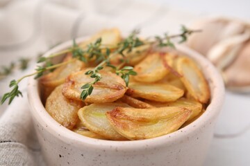 Fried garlic cloves and thyme in bowl on table, closeup