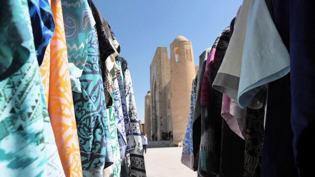 Trade stalls with traditional textiles and products in the old city of Bukhara, Uzbekistan. Fabric with a national pattern flutters in the wind