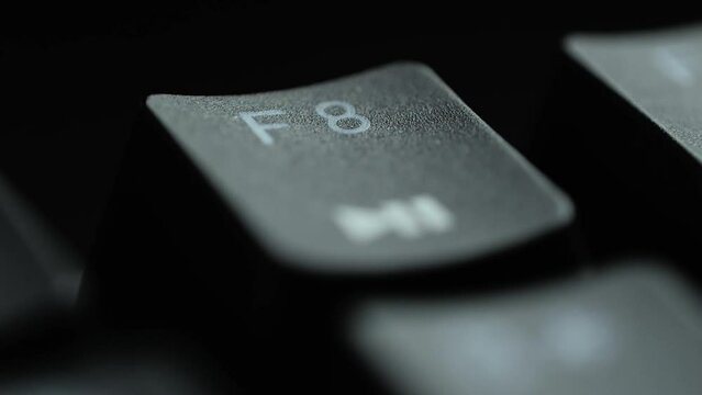 Keyboard button F8. Macro shot of finger pressing F8 button