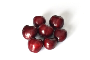 Several fruits of ripe red cherries lie on white.