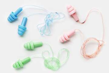 Reusable silicone colorful earplugs, for swim, sleep, rest as minimal trend pattern on white background. Soft, flexible ear plug on cord against noise, protect hear, close up, top view