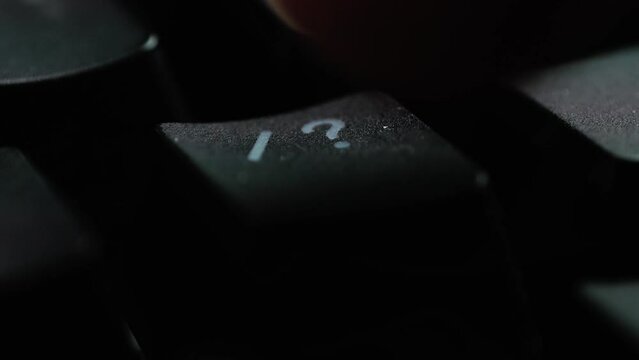 Keyboard button FORWARD SLASH. Macro shot of finger pressing QUESTION MARK button