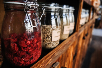 Glass Jars of Assorted Organic Freeze-Dried Foods on Wooden Shelf. Glass jars filled with various dried fruit, Raspberries, herbs and seeds, showcasing an organized pantry setup.