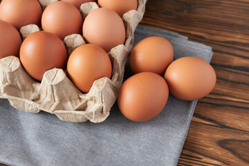 Eggs in a cardboard box on a napkin and a wooden table, close-up