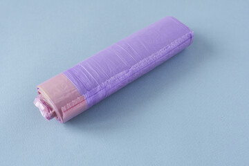 Plastic garbage bags. Roll of lavender colored trash bags on blue background. Close-up.