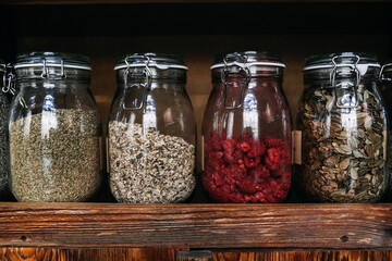 Glass Jars of Assorted Organic Freeze-Dried Foods on Wooden Shelf. Glass jars filled with various...