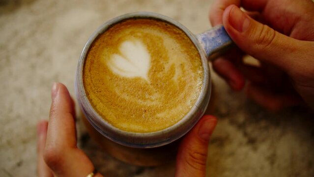 Coffee cup with a painted heart stands on the table with, close up view