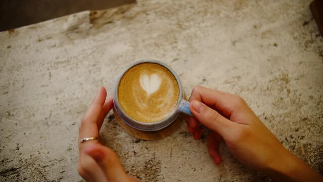A coffee cup with a painted heart on a wooden table, top view