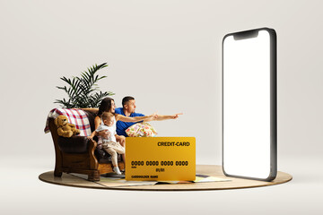 Happy young family, man, woman and child sitting on couch with credit card and pointing at 3D model...