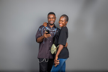 Photo of positive excited people man and woman smiling and looking at their mobile phones isolated...