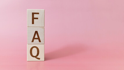 FAQ text on wooden cubes on a pink background, copy space. Frequently asked questions support...