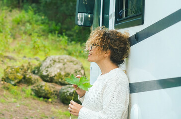 One serene woman enjoy relax and calm outdoors standing outside a camper van and admiring green...