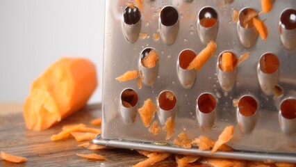 Close-up shot of a pile of grated carrots under a metal grater.