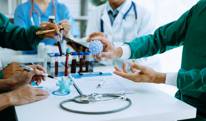 Medical team having a meeting with doctors in white lab coats and surgical scrubs seated at a table...