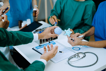Medical team having a meeting with doctors in white lab coats and surgical scrubs seated at a table...