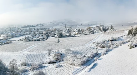 Zelfklevend Fotobehang Aerial image of the snow-covered village surrounded by frozen vineyard in Hallau, Klettgau, Schaffhausen, Switzerland © Yü Lan