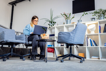 Young women sitting in coworking space working while using laptop.