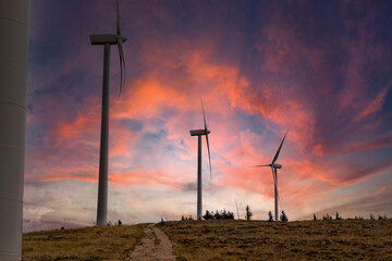 Obraz premium Scenery mountain in winter with a wind farm at sunset Wind turbines for green economy and technology are the only solution to protect the planet from climate change and global warming natural industry