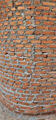Vertical image of a red brick wall that forms a curved wall. Red bricks were arranged in...