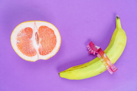a cock penis stimulation ring, grapefruit and banana isolated on a purple background. The concept of using sex toys to prolong sexual intercourse in men and stimulate the clitoris of women.