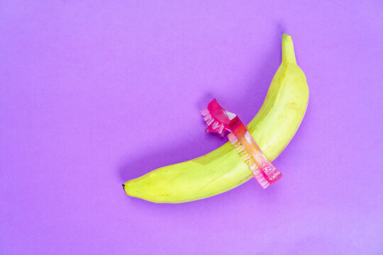 a cock penis stimulation ring and banana isolated on a purple background. The concept of using sex toys to prolong sexual intercourse in men and stimulate the clitoris of women.