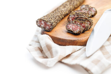 Smoked dried sausage. Sliced sausage on cutting board isolated on white background.