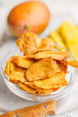 Dried mango fruit in bowl on white table.